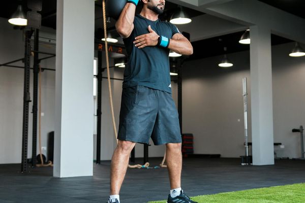 Man performing a controlled kettlebell swing in a modern gym.
